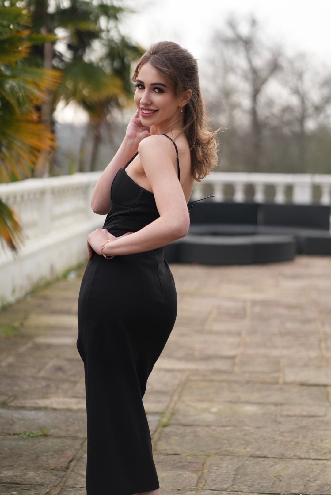 Vyacheslavivna in profile wearing a black evening dress outdoors