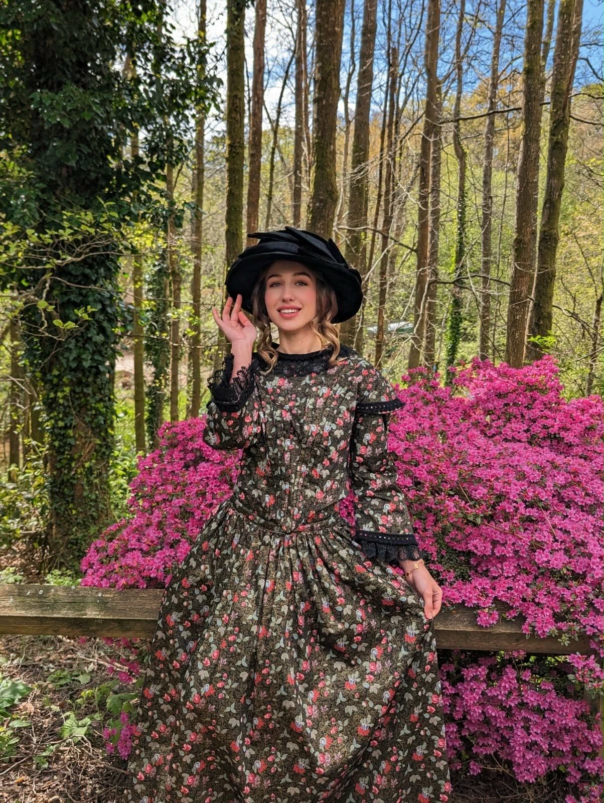 Iryna Vyacheslavivna wearing a floral dress and black hat in a garden